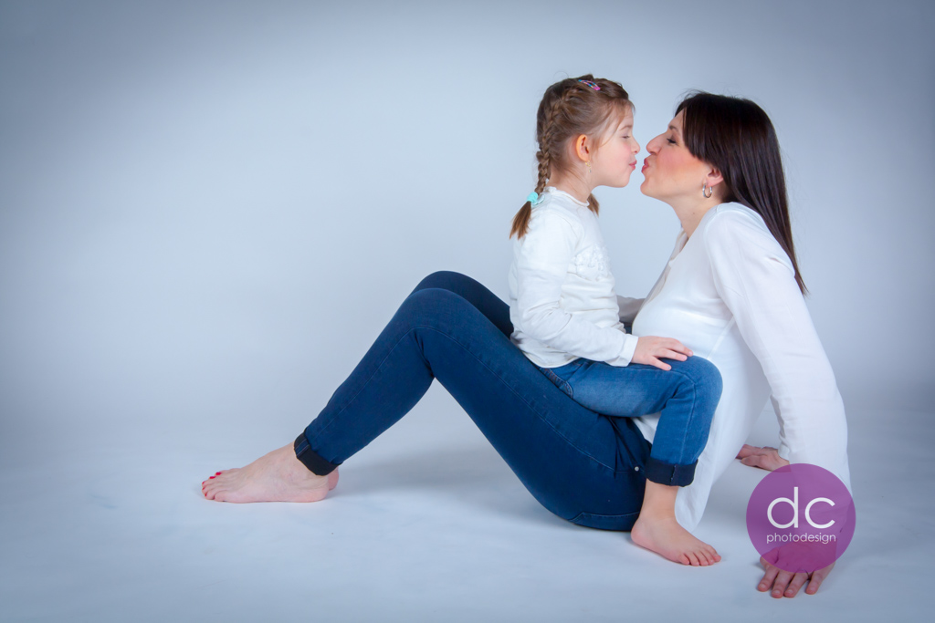 Ein Fotohooting mit Mutter und Tochter, bei dem sich Mutter und Tochter einen Kuss geben.