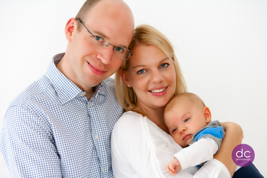 Neugeborenes Fotoshooting bei dem junge Eltern ihr Baby auf dem Arm der Mutter halten