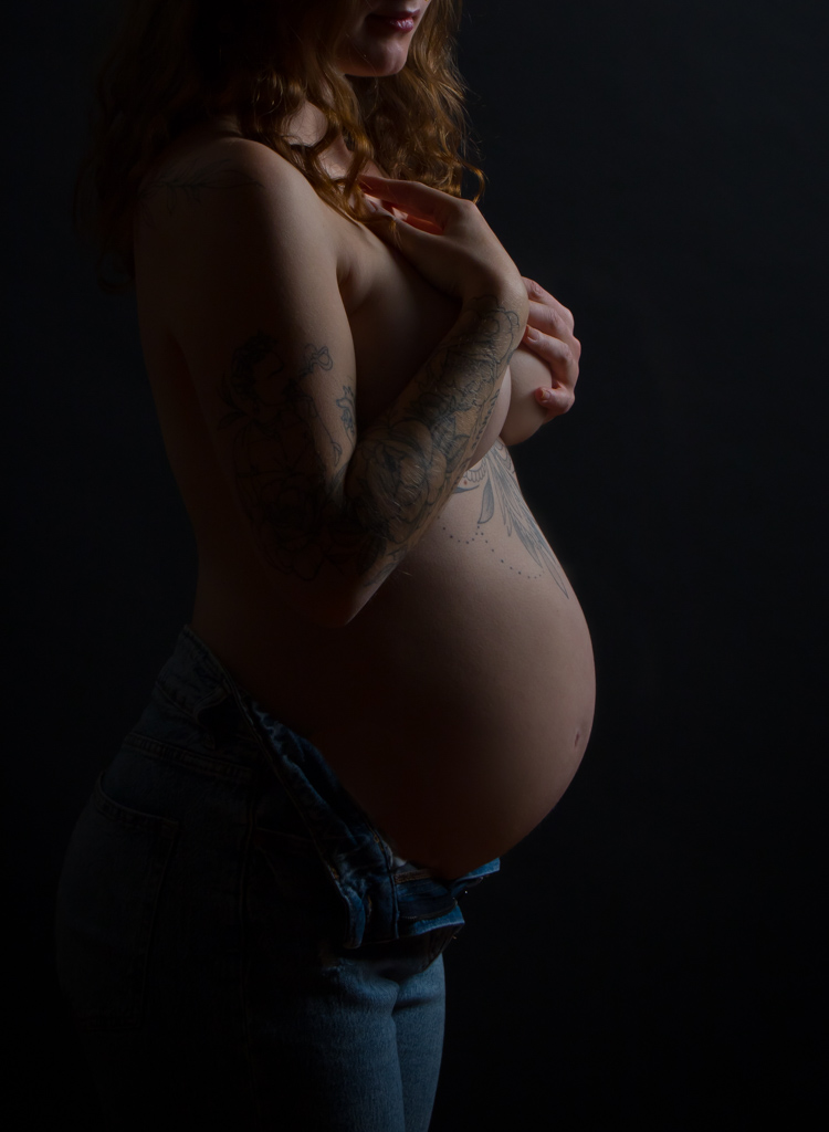 Babybauch Fotoshooting einer schwangeren Frau die ihre Hände auf der Brust hält